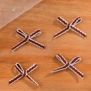 Dettaglio di mini fiocchi di nastro marroni con frange bianche per vestiti