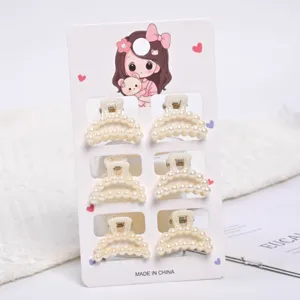 Detail shot of six small elegant pearl hair claw clips on decorative card packaging