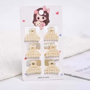 Detailed view showing six small cream pearl hair claws on a decorative display card.