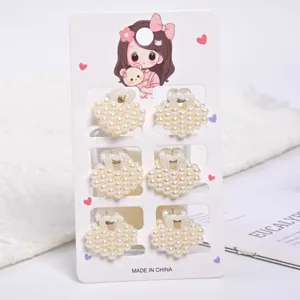 Close-up of six elegant heart-shaped white pearl mini claw clips on a display card