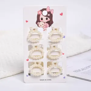 Detail view of six small pearl hair claw clips attached to a decorative cardboard display card