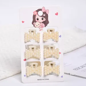 Detailed view of six small elegant pearl claw hair clips on a decorative display card
