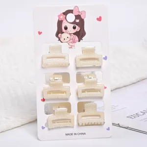 Detail showing six small cream pearl hair claw clips on a cute illustrated display card.