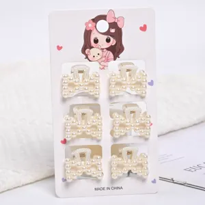 Detailed view of six small elegant faux pearl hair claw clips on a cute display card
