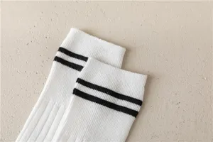Nahaufnahme von weißen Baumwollsocken mit schwarzen Doppelstreifen und feiner Rippstricktextur.