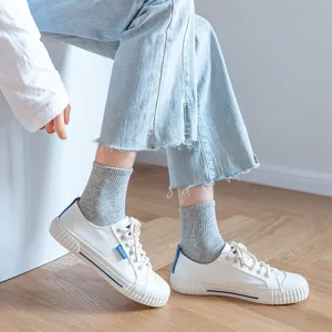 Classic white canvas sneakers paired with comfortable grey socks and stylish light blue jeans.