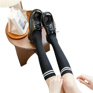 Klassische schwarze Kniestrümpfe mit weißen Streifen und stylischen Schuhen für Damen.