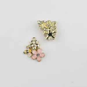 Détail en gros plan de charmants pendentifs abeille et fleur en alliage pour bijoux DIY.