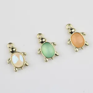 Close up of cute turtle charms, gold metal with colorful resin stones for DIY jewelry crafts.