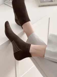 Detailed shot of breathable mesh brown ankle socks with side stripe design worn on foot.