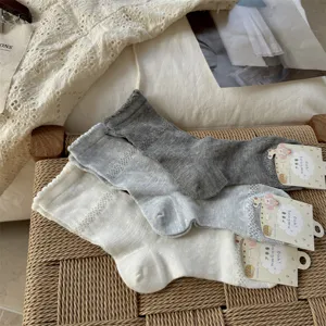 Detailed view of women's thin mesh mid-calf socks in white and grey colors with breathable dot design.