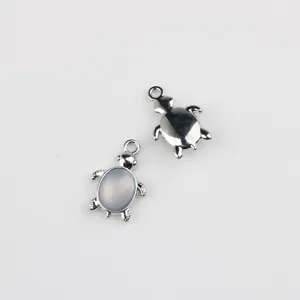 Close-up detail of silver alloy turtle pendant charms with stone inlay for DIY jewelry making.