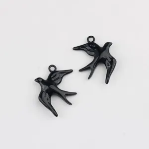 Gedetailleerde close-up van zwart geëmailleerde zwaluw bedels voor eigen sieraden maken.