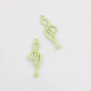 Primer plano de dijes conectores de lazo de aleación pintada verde claro para joyería DIY.