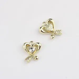 Detail view of gold alloy heart arrow pendants, perfect for DIY jewelry charm making accessories.