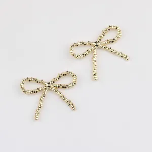Detailaufnahme goldener Schleifen-Anhänger mit strukturierter Oberfläche zum Basteln.