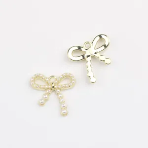 Close-up detail of gold alloy bow charms with faux pearls, ideal for DIY jewelry making.