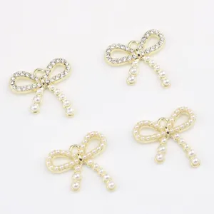 Close-up detail shot of gold alloy bowknot pendant charms inlaid with sparkling pearls and zircon.