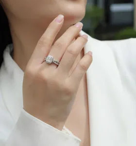 Gros plan détaillé de bague en moissanite taille émeraude avec halo et anneau croisé.
