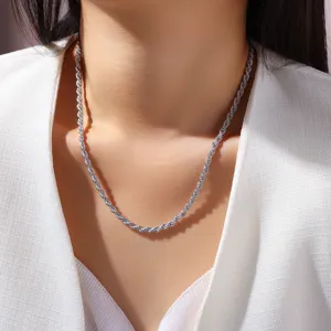 Gros plan d'un collier en chaîne torsadée couleur argent porté par un mannequin en haut blanc.