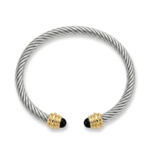 Gedetailleerd uitzicht van de gedraaide kabelarmband in zilver- en goudtoon met zwarte einden.