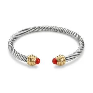 Roestvrijstalen kabel manchetarmband detail, getwist draadontwerp met 18k goud en rode stenen.