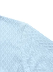 Détail rapproché d'un pull en maille bleu clair montrant la texture jacquard complexe.