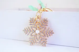 Primo piano di un portachiavi a fiocco di neve dorato con strass scintillanti e perla.