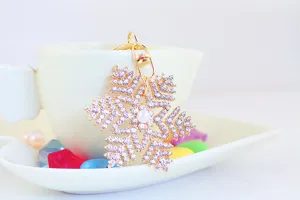 Primo piano di un portachiavi a fiocco di neve dorato con strass luccicanti e perla.