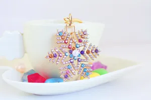 Dettaglio di un portachiavi a fiocco di neve con strass colorati e perla centrale.