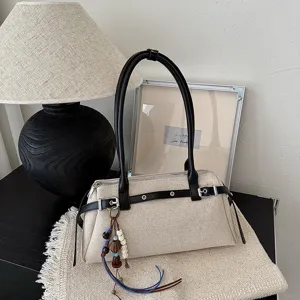 Vue détaillée du sac à main rétro en toile beige avec anses en cuir noir et charmant.