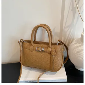 Elegante bruine lederen handtas voor dames, stijlvolle emmertas met schouderriem en gesp.