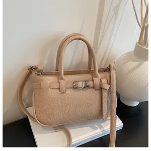 Close-up van de beige gestructureerde lederen handtas met stijlvol gespriemdetail.