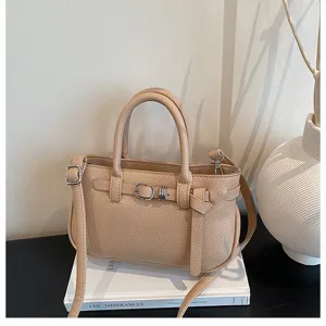 Gedetailleerd overzicht van trendy beige handtas van kunstleder met gesp en metalen details.