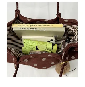 Detail view of a stylish brown polka dot tote bag with large capacity, interior storage and stripes.