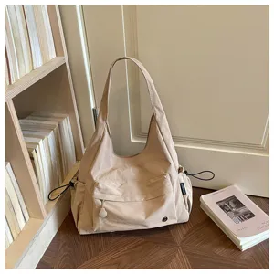 Primo piano dei dettagli della borsa a spalla beige, con tasca laterale e design minimalista.