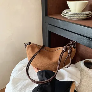 Détail de sac porté épaule croissant en suédine marron, sac boulette vintage poignée.