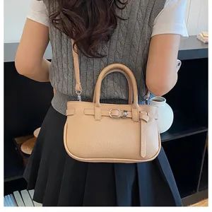Gedetailleerd shot van de elegante beige lederen handtas met fijne riem en metalen gesp.