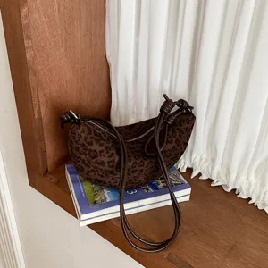 Gros plan d'un sac porté épaule imprimé léopard marron foncé posé sur des livres décoratifs.
