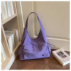 Vista dettagliata della borsa a spalla viola minimalista con tasca anteriore in scena.