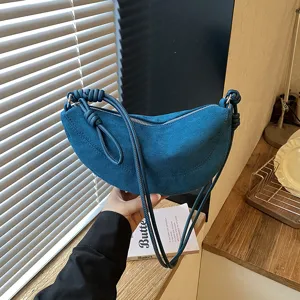 Gros plan sur le sac bandoulière croissant en suédine bleue, détail chic de sac besace quotidien.
