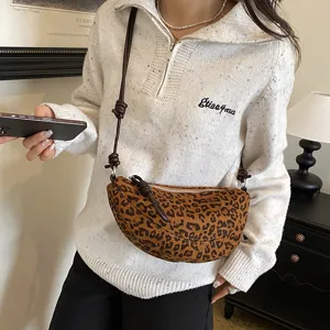 Détail de sac bandoulière imprimé léopard, sac croissant chic avec une lanière nouée.