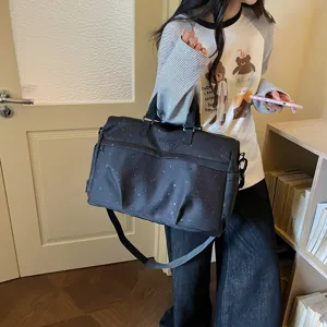 Detail view of a black star and moon print travel tote bag with sturdy straps and large space.
