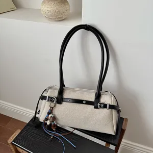 Vue détaillée du sac baguette vintage en toile avec lanières en cuir noir et boucles chics.