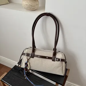 Gros plan détaillé du sac à main en toile beige avec garniture en cuir et perles.
