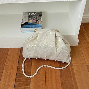 Elegant pearl embellished ruched clutch bag with pearl chain strap, detail view showcasing texture.