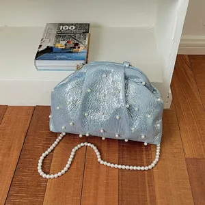 Detail shot of light blue metallic crinkled evening bag with pearl embellishments and strap.