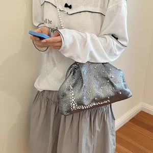 Detail shot of metallic silver clutch bag featuring exquisite pearl embellishments and soft texture.