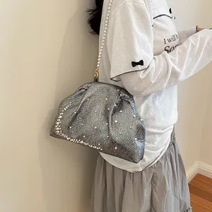 Detail shot of the metallic shell shoulder bag showcasing elegant pearl details and chain.