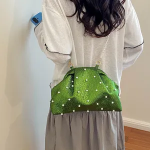 Detail view of stylish green metallic pearl clutch shoulder bag with elegant pearl chain.